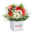 Capturing the lively spirit of Marks Gate's local gardens, this beautifully composed bouquet radiates effortless joy. In a meticulously clean white gift bag with neatly looped handles, a symphony of coral, peach, and bold red carnations bloom with plush, ruffled petals-each touch inviting a sense of warmth. Interspersed among these vibrant blooms, white daisies with glimmering yellow-green eyes smile forth, hinting at the optimism of spring days in the local parks. Misty sprays of baby's breath hover among the flowers, their airy, delicate petals bringing softness and innocence, while a few gracefully concealed purple-tipped buds add intrigue at one edge. Lush arcs of deep green, polished foliage cradle the blooms, suggestive of leafy walks and tree-lined neighbourhood streets. The display forms a naturally rounded, bountiful shape-suggesting both abundance and thoughtful design. The bouquet stands ready for gifting, its fresh, celebratory feel perfectly suited for a birthday, anniversary, or simply as a cheerful surprise delivered to a doorstep in Marks Gate. Every detail, from the interplay of colours to the expertly placed greenery, reflects the artistry and heart that defines this local floral creation.